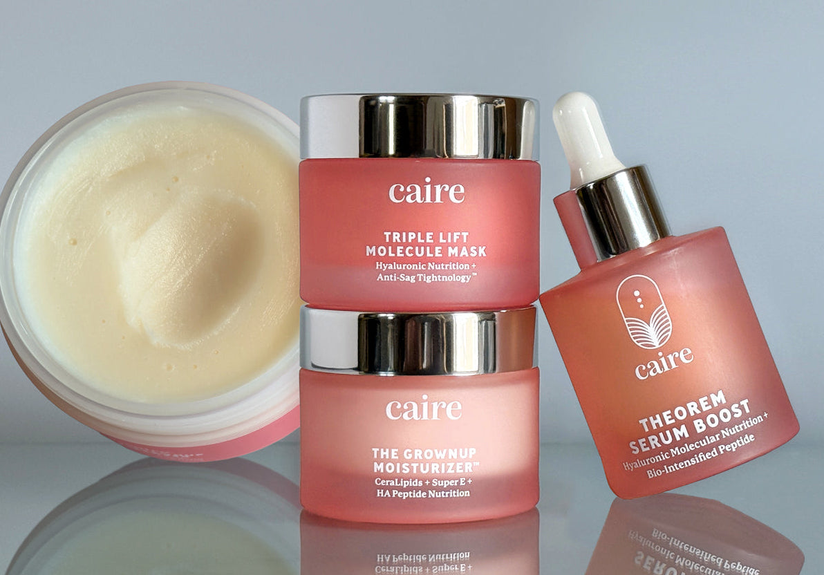 Caire skincare products including a jar, cream, and serum on a reflective surface with a gray background