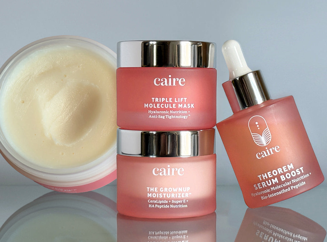 Caire skincare products including a jar, cream, and serum on a reflective surface with a gray background